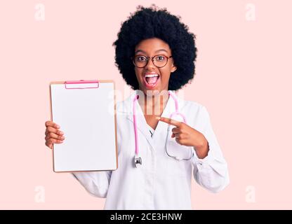 Giovane donna afroamericana indossando stetoscopio medico tenendo appunti sorridente buon puntamento con mano e dito Foto Stock