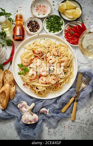 Spaghetti con gamberi su piastra di ceramica bianca e serviti con un bicchiere di vino bianco Foto Stock