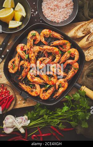 Gustosi gamberi arrosto con spezie in padella con ingredienti su fondo arrugginito Foto Stock