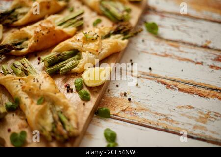 Asparagi verdi al forno avvolti in pasta sfoglia. Servita su tavola di legno. Con spazio per la copia Foto Stock