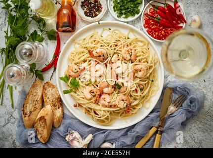 Spaghetti con gamberi su piastra di ceramica bianca e serviti con un bicchiere di vino bianco Foto Stock