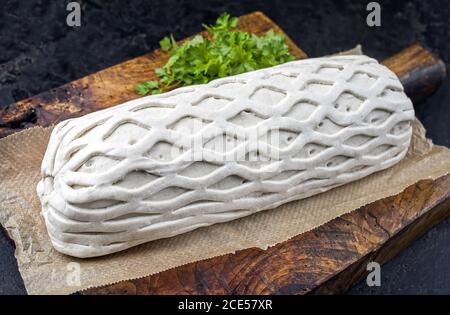 Carne di maiale cruda Kasseler come pezzo in pasta sfoglia come closeup offerto su un tagliere di legno con erbe Foto Stock