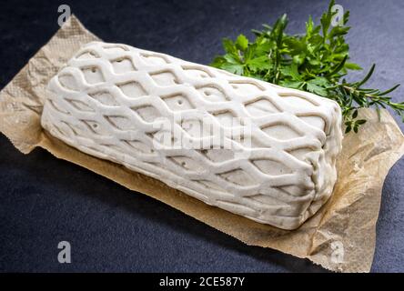 Bistecca di maiale cruda Kasseler come pezzo in pasta sfoglia con erbe come closeup offerto su carta marrone e sfondo nero con spin. copia Foto Stock