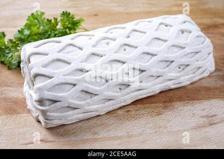 Carne di maiale cruda Kasseler come pezzo in pasta sfoglia come closeup offerto su un tagliere di legno con erbe Foto Stock