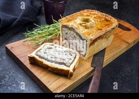 Tradizionale francese Pate en croute con pollo offerto come closeup su un tagliere dal design moderno Foto Stock