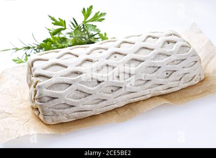 Bistecca di maiale cruda Kasseler come pezzo in pasta sfoglia con erbe come closeup offerto su carta marrone e sfondo bianco con spin. copia Foto Stock