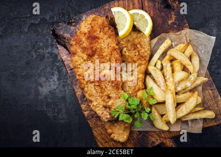Wiener schnitzel fritto dalla parte superiore di vitello con patatine fritte e. fetta di limone come vista dall'alto su un vecchio taglio rustico scheda con copia Foto Stock