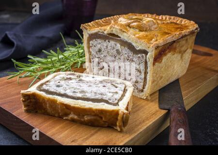 Tradizionale francese Pate en croute con pollo offerto come closeup su un tagliere dal design moderno Foto Stock