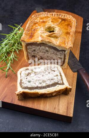 Paté en croute francese tradizionale con pollo offerto come closeup su un tagliere dal design moderno Foto Stock