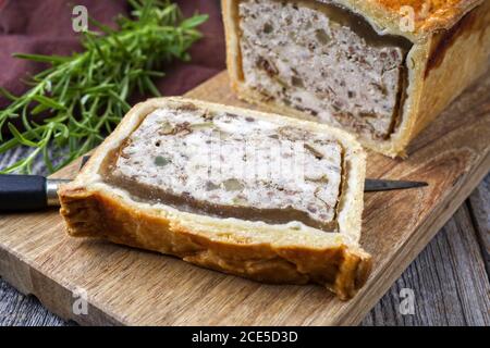 Tradizionale francese Pate en croute con pollo offerto come closeup su un tagliere dal design moderno Foto Stock