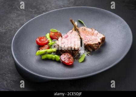 Griglia di collo di agnello con paprika e pomodoro offerto come primo piano su una piastra di design moderno Foto Stock