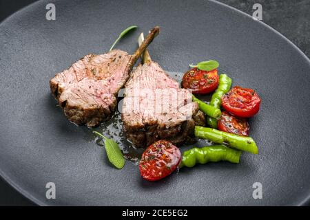 Griglia di collo di agnello con paprika e pomodoro offerto come primo piano su una piastra di design moderno Foto Stock