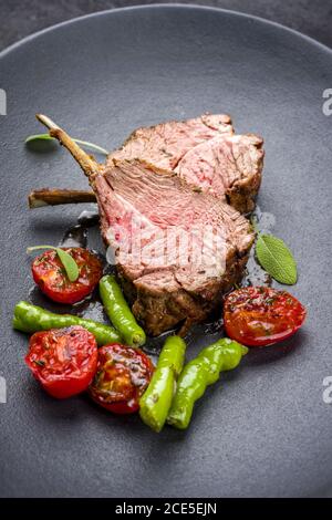 Griglia di collo di agnello con paprika e pomodoro offerto come primo piano su una piastra di design moderno Foto Stock