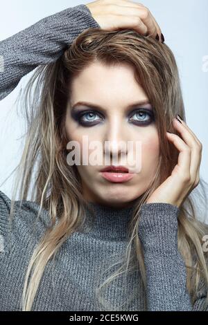 Bionda giovane bella donna vestita con pullover bianco di lana. Foto Stock