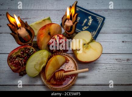 Prodotti tradizionali per la celebrazione del Rosh Hashanah - mele, melograno, miele, favi - su sfondo bianco di legno Foto Stock