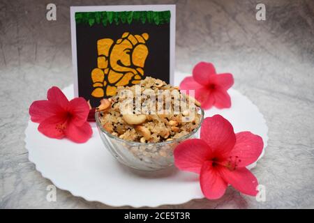 Happy Ganesh chaturthi speciale prasadam dolce piatto festival articolo Panchakajjaya offerto a Ganapati con fiori rossi ibisco su sfondo bianco. INDI Foto Stock