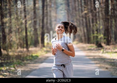 Bella giovane donna in esecuzione nel parco verde sulla soleggiata giornata estiva Foto Stock