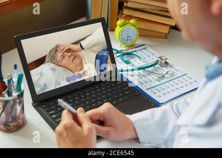 Il medico consulta una donna anziana malata. Lavorare online. Foto Stock