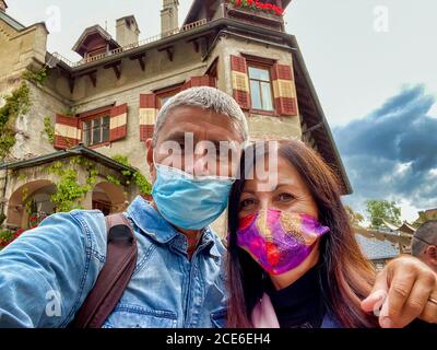 Coppia che indossa maschere visitando la città delle alpi. Foto Stock