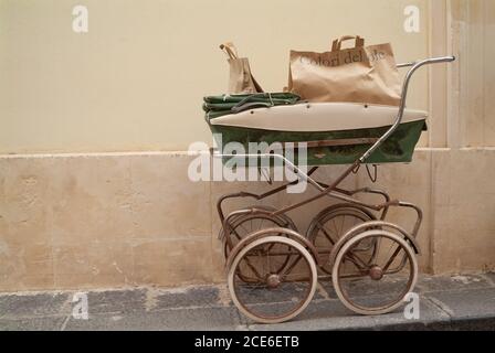 Carrozza vintage esposta all'esterno di un negozio per bambini. Ortigia area urbana. Siracusa Siracusa, Sicilia Italia, stagione estiva Foto Stock