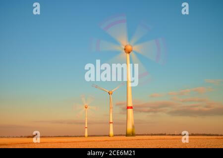 Turbine eoliche moderne che producono energia nella soleggiata mattina primaverile. Effetto tonalità vintage Foto Stock