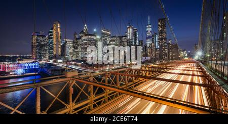 Vista panoramica sui grattacieli di Lower Manhattan al Dusk e al Ponte di Brooklyn con sentieri luminosi. Serata a New York City, NY, USA Foto Stock