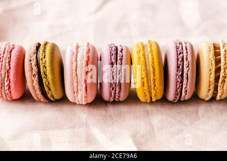 Primo piano di deliziosi macaron assortiti posti su un tavolo rosa Foto Stock