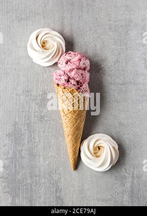 Vista dall'alto del gelato alla ciliegia fatto in casa al waffle cono posto sul tavolo con meringhe Foto Stock