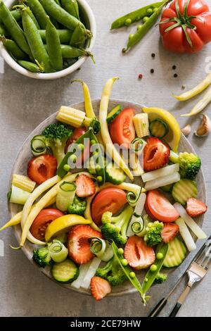 Vista dall'alto di deliziosi pomodori sani e cetrioli piatto con piselli e fagioli verdi sul tavolo in cucina Foto Stock