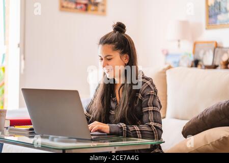 Giovane donna che lavora con il laptop in salotto Foto Stock