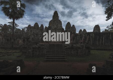 Esterno intemperie dello storico complesso Angkor Wat contro il cielo nuvoloso In Cambogia Foto Stock