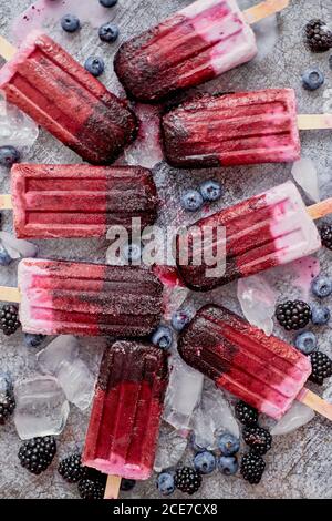 frullato e gelati o popsicle fatti in casa con bacche surgelate su vassoio di ardesia nero Foto Stock