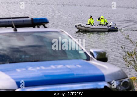 Dresda, Germania. 28 Agosto 2020. Poliziotti della polizia dell'acqua con motoscafo su un lago. In primo piano ha lasciato una macchina di polizia. Credit: Tino Plunert/dpa-Zentralbild/ZB/dpa/Alamy Live News Foto Stock