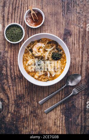 Vista dall'alto del piatto di risotto con funghi e. gamberi serviti su tavola di legno Foto Stock