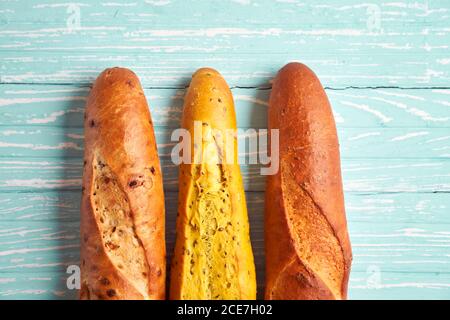 Tre baguette croccanti francesi giacciono baguette blu di legno di fondo in assortimento con semi di sesamo dolci classici nazionali francesi Copy Space Concept Foto Stock