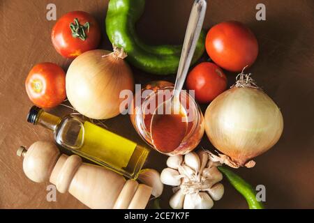 Composizione vista dall'alto con salsa di pomodoro in vasetto posto in mezzo verdure fresche e olio d'oliva con spezie preparate per cucinare Salsa bolognese Foto Stock