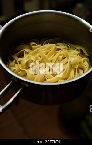 Dall'alto di deliziosa pasta italiana su pentola in acciaio inox su superficie in cucina Foto Stock