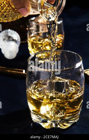persona anonima che serve il whisky in un bicchiere Foto Stock