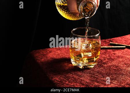 persona anonima che serve il whisky in un bicchiere Foto Stock