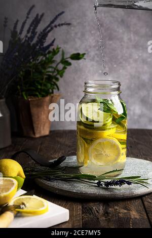 Vista laterale ancora vita di limonata in un vaso di vetro, posto su un tavolo di legno Foto Stock