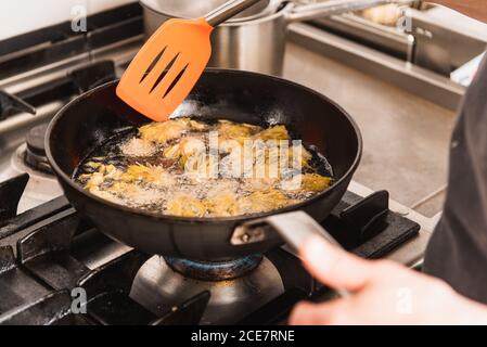 Cuoco femminile tagliato e irriconoscibile frittura carciofi in cucina di un ristorante Foto Stock