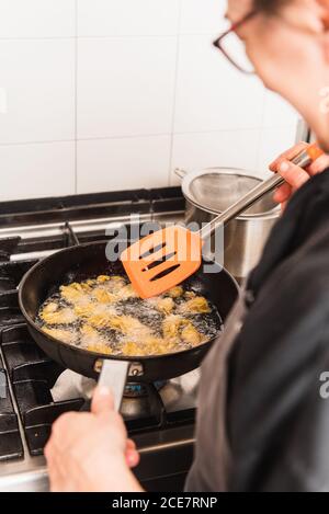 Cuoco femminile tagliato e irriconoscibile frittura carciofi in cucina di un ristorante Foto Stock