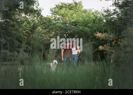 Tenera coppia felice abbracciarsi mentre si sta con Old Inglese Sheepdog in giardino il giorno di sole Foto Stock