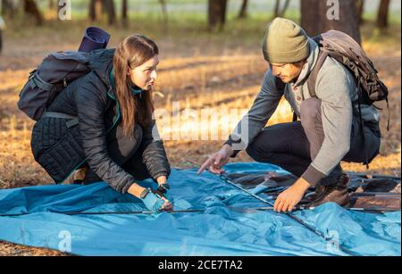 Coppia di escursionisti che lanciano la tenda prima di un tramonto Foto Stock