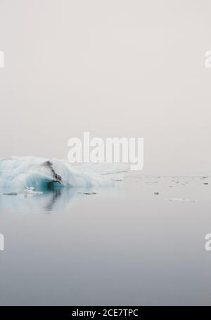 Magnifica vista di grandi iceberg circondato da mare silenzioso con Increspature sulla superficie in condizioni atmosferiche sovrastanti in inverno in Islanda Foto Stock