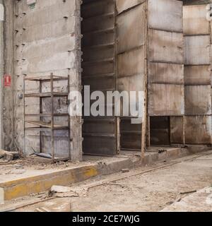 Pareti in legno intemperie e pavimento in cemento armato in vecchio edificio di pianta abbandonata Foto Stock