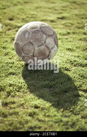 Dall'alto della palla da calcio in pelle usata con motivo esagonale e superficie di scabvicino su prato verde coperto di erba sintetica rotolo Foto Stock