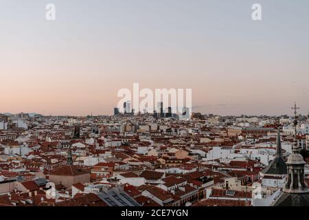 Dall'alto si può ammirare una vista spettacolare della tipica residenza densamente costruita Quartiere della città di Madrid con case basse con rosso tetti visti dal tetto durante il tramonto in estate sera Foto Stock