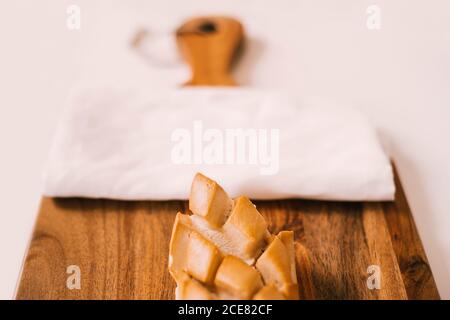 Pane fresco servito su tagliere di legno su tavola bianca durante la prima colazione Foto Stock