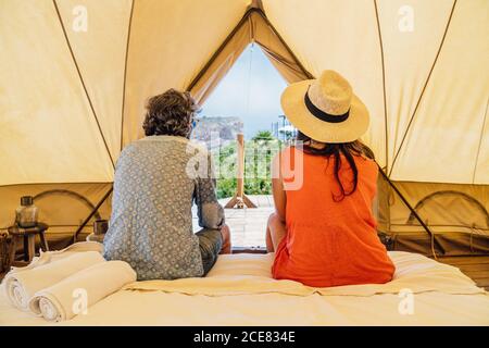 Coppia matura felice a lunghezza intera in un abbigliamento casual estivo seduto sul letto in campeggio di lusso e guardando via con tenerezza Foto Stock